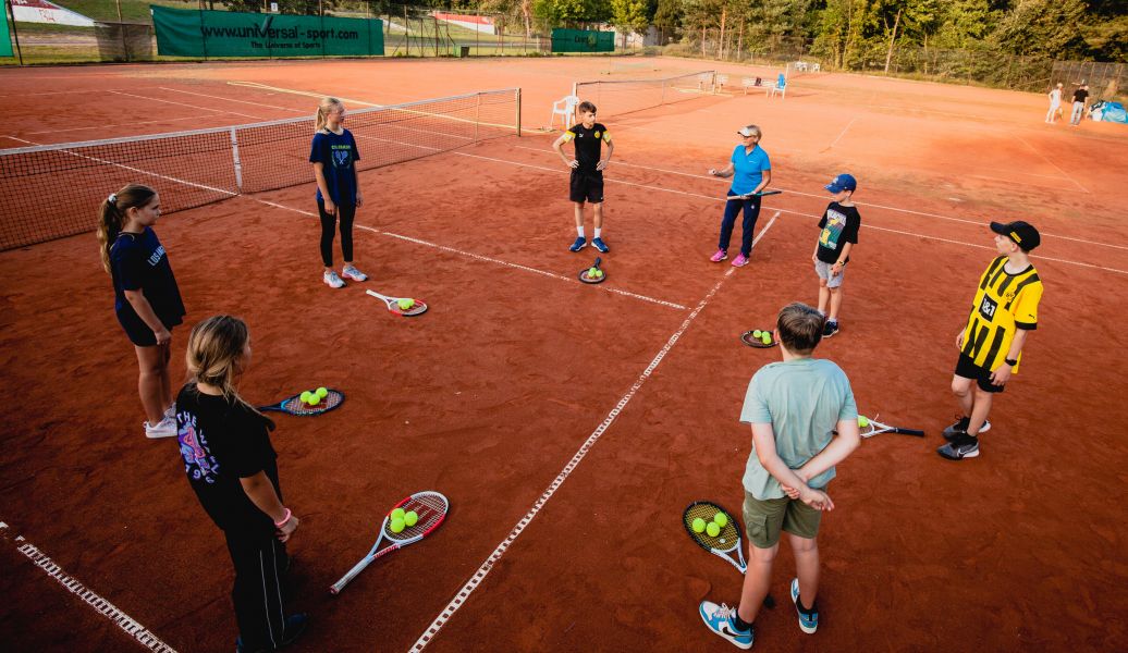 Eine kleine Gruppe von Kindern die Tennistraining haben
